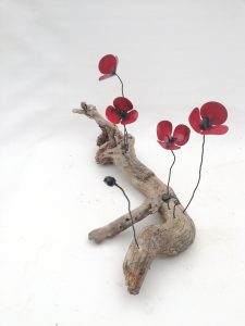 Amapolas de forja sujetas a una raíz de árbol