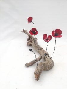 Amapolas de forja sujetas a una raíz de árbol