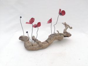 Amapolas de forja sujetas a una raíz de árbol