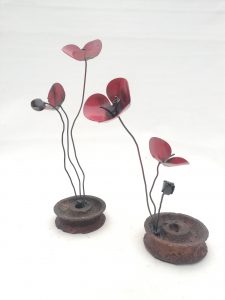 una flor de forja sujeta a una rueda de metal, llamada amapola rueda metal.