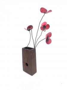 cuatro amapolas de forja sujetas a un metal que hace de jarrón. Amapola jarrón metal