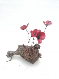 Amapolas de forja sujetas a una raíz de árbol