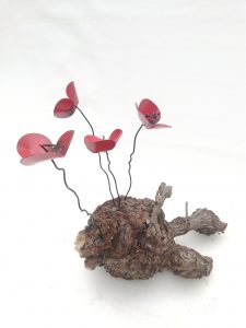 Amapolas de forja sujetas a una raíz de árbol