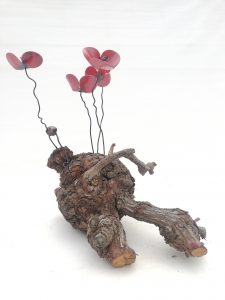 Amapolas de forja sujetas a una raíz de árbol