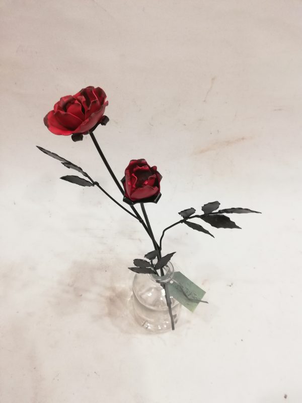 dos rosas de forja en un recipiente de cristal