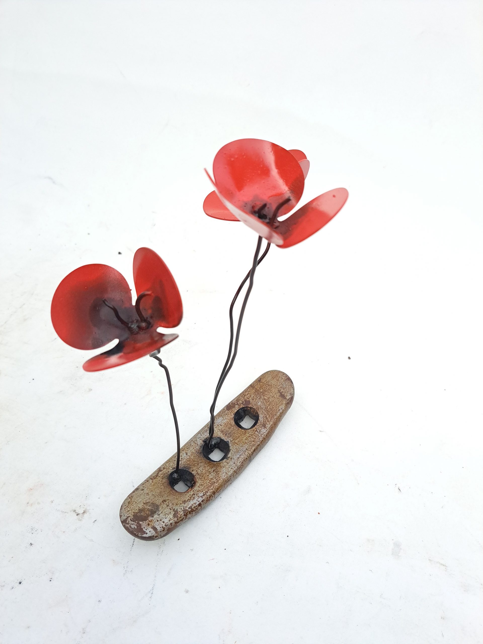 Amapolas rojas de metal en una base de acero industrial oxidada