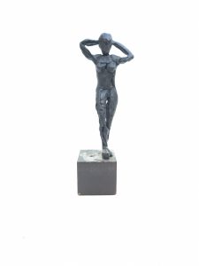 Escultura de una figura femenina modelada en resina epoxi en posición de pie y con los brazos descansando detrás de la cabeza. La figura está en una base de acero macizo a modo de pedestal.